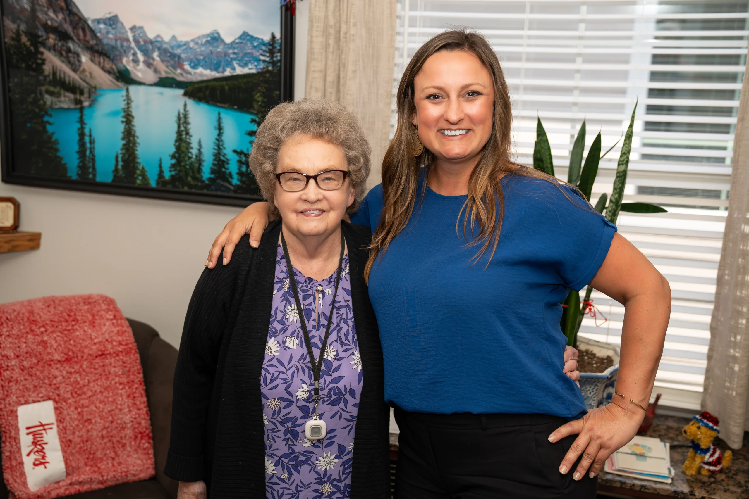Elderly person and woman smiling at camera standing next to eachother